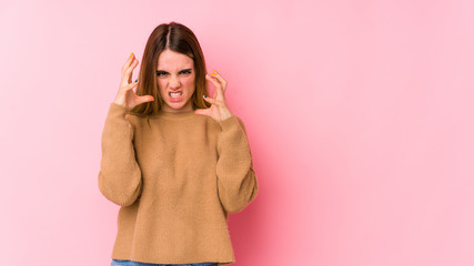 Young caucasian woman isolated on pink background upset screaming with tense hands.