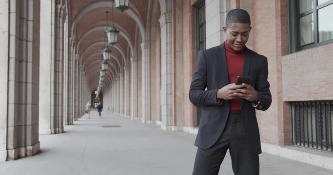 attractive black Hispanic young guy male businessman successful manager in a classic suit uses his smartphone