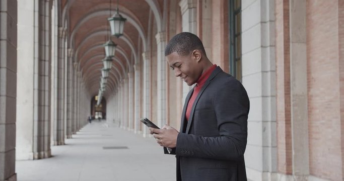 attractive black Hispanic young guy male businessman successful manager in a classic suit uses his smartphone