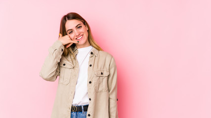 Young caucasian woman isolated on pink background showing a mobile phone call gesture with fingers.