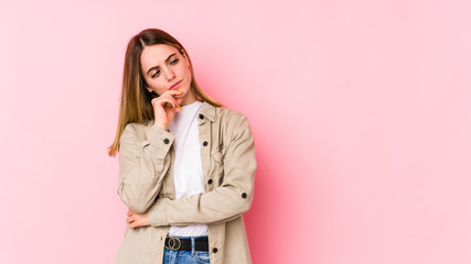 Young caucasian woman isolated on pink background looking sideways with doubtful and skeptical...