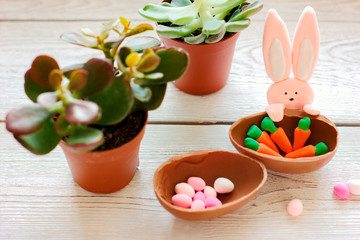 happy easter decorations. toy bunny, chicken and chocolate egg with carrot decor. succulent spring flowers. festive kids design for easter.