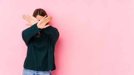 Fototapeta premium Young caucasian woman isolated on pink background keeping two arms crossed, denial concept.