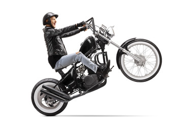 Young biker riding a custom motorbike on one wheel