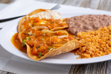 A view of a plate of huevos rancheros, in a restaurant or kitchen setting.