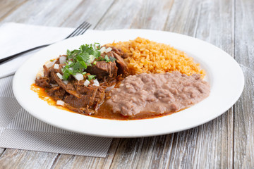 A view of a plate of beef birria, in a restaurant or kitchen setting.