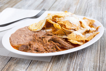 A view of a plate of birria and chilaquiles in a restaurant or kitchen setting.