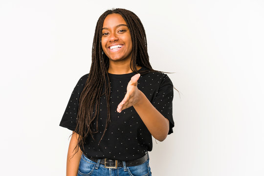 Young african american woman isolated on white background stretching hand at camera in greeting gesture.