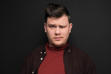 Portrait of young perplexity man isolated on gray background