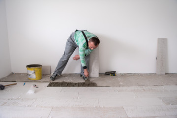 worker installing the ceramic wood effect tiles on the floor