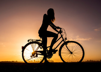 Girl on old bicycle at sunset