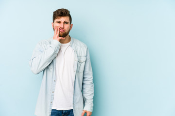 Young caucasian man isolated on blue background having a strong teeth pain, molar ache.