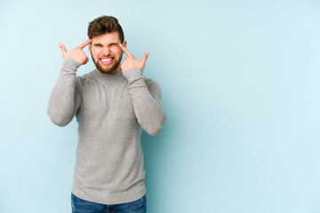 Young caucasian man isolated on blue background showing a disappointment gesture with forefinger.