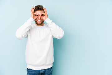 Fototapeta premium Young caucasian man isolated on blue background excited keeping ok gesture on eye.