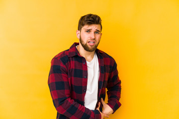 Young caucasian man isolated on yellow background having a liver pain, stomach ache.