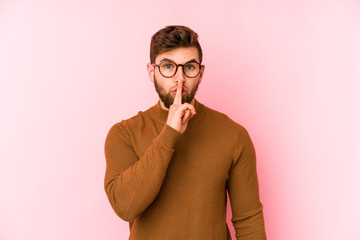 Obraz premium Young caucasian man isolated on pink background keeping a secret or asking for silence.