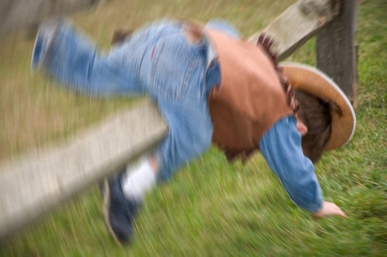Toddler boy dressed up as a cowboy falling over a post in a field in New Jersey.