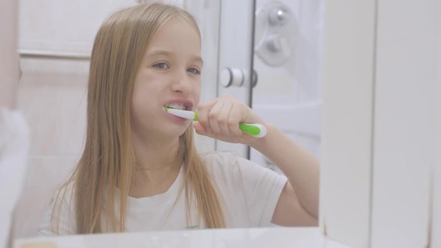 Pre teen girl brushes her teeth and washing his face in the bathroom.