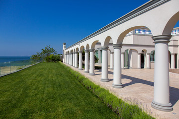 Obraz premium arched structure with columns architecture with a flower bed of lavender and green meadow on summer sunny day with blue sky.