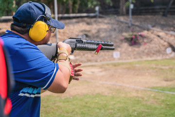 selective focus of man holding and fire shortgun in shooting range of gun shooting competition