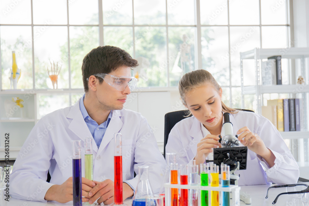 Poster male and female scientists working in a science laboratory with various equipment in the laboratory.