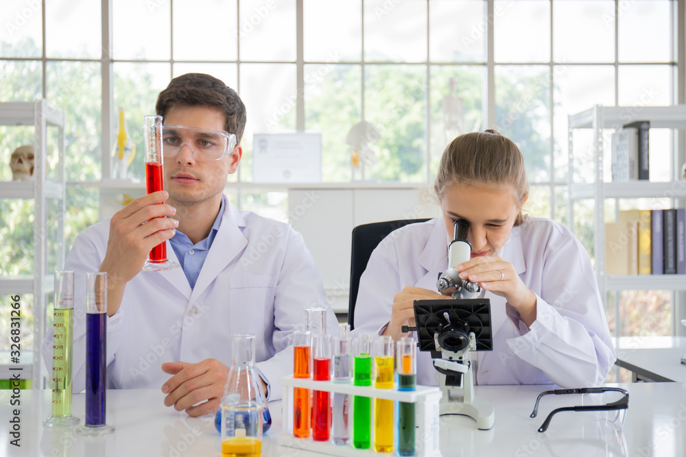 Poster male and female scientists working in a science laboratory with various equipment in the laboratory.