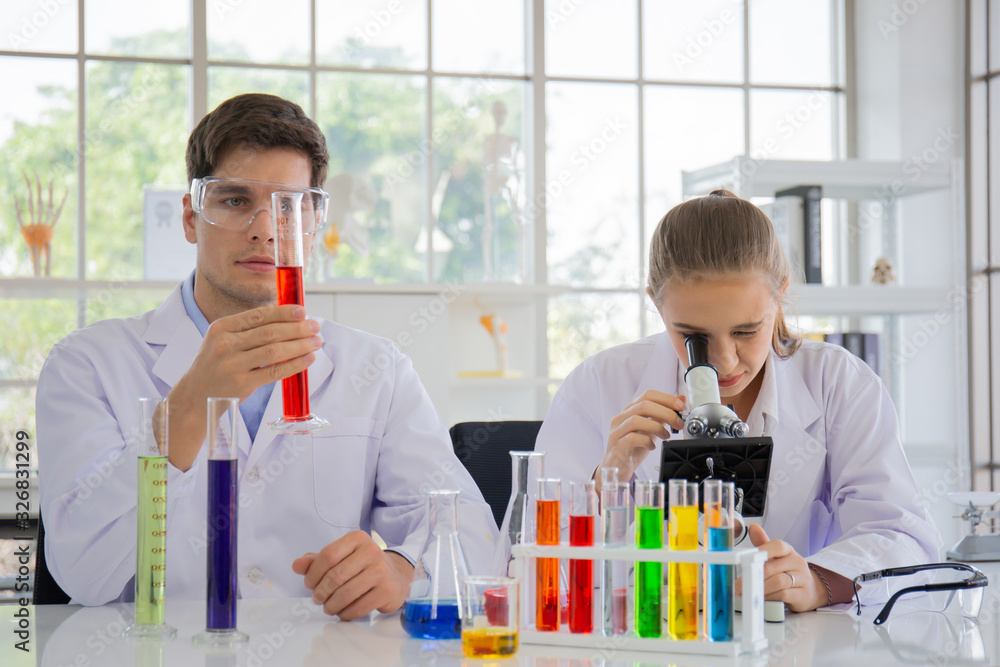 Poster male and female scientists working in a science laboratory with various equipment in the laboratory.