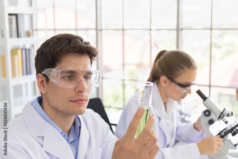 Poster male and female scientists working in a science laboratory with various equipment in the laboratory.