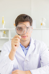 The male doctor looking through the magnifying glass in the lab