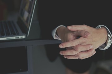 A businessman dressed in a suit sits at a desk with his hands clasped showing power and confidence.