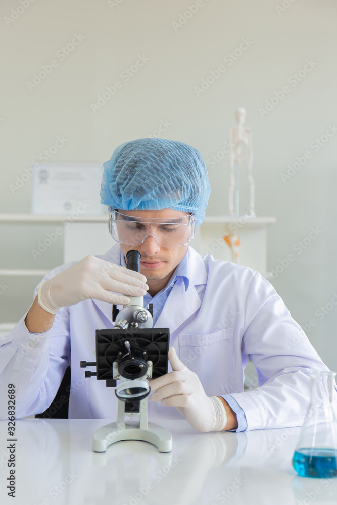 Poster Young Scientist using Microscope in Laboratory. Male Researcher wearing white Coat sitting at Desk and looking at Samples by using Microscope in Lab. Scientist at Work in Laboratory