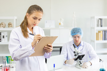 Scientists, young men and women in the laboratory and have a beautiful orange light.