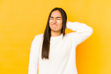 Fototapeta premium Young woman isolated on a yellow background suffering neck pain due to sedentary lifestyle.