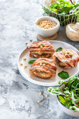 Large mushrooms stuffed with cheese and pine nuts baked in bacon. Beautiful and colorful holiday snack. Dish for catering.