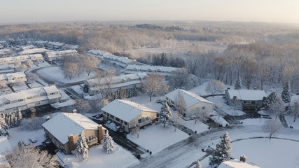 Aerial view of residential houses, condo, townhouses covered snow at winter season. Establishing shot of american neighborhood, suburb at wintertime.  Real estate, Midwest, sunny morning