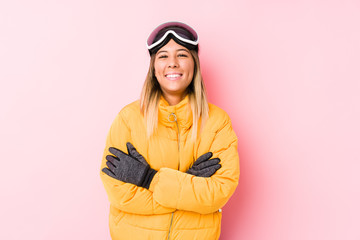 Young caucasian woman wearing a ski clothes in a pink background laughing and having fun.