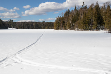 Fototapeta na wymiar Tracks across a frozen lake in Muskoka on winter day