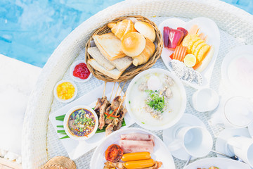 Floating breakfast set in tray with fried egg omelette sausage ham bread fruit milk juice coffee