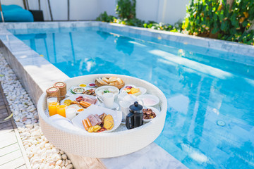 Floating breakfast set in tray with fried egg omelette sausage ham bread fruit milk juice coffee