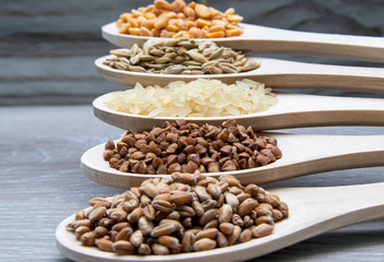 Composition of wooden spoons on which grains and cereals are located. Wheat, rice, buckwheat, millet, oats.