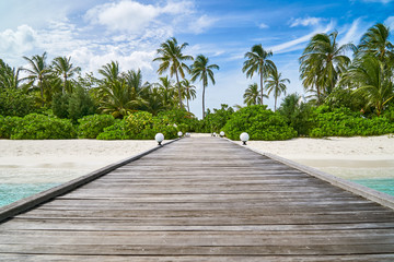 Wooden jetty to the tropical beach on Maldives island.
