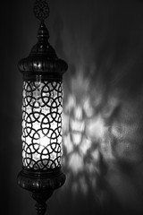 Fototapeta na wymiar Old lantern against the wall black and white cast shadows. Vintage design and antique lamp background 