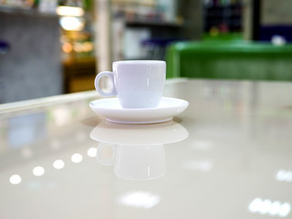 White little cup of espresso coffee on a table in a cafe. Defocused room