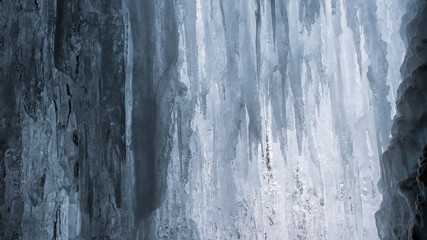 Frozen waterfall ice and hanging icicles freezing wall background. Canadian winter landscape and nature wallpaper