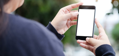 Cropped shot view of woman hands holding smart phone with blank copy space screen for your text message or information content, female reading text message on cell telephone during in urban setting.
