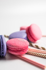 Obraz na płótnie Canvas Colorful purple and pink macaroons and drinking tubes on a light background. Food photo. Food photography. Close up. Simplicity. Minimalism.