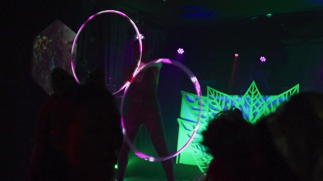 Performer in costume spinning multiple colorful hula hoops in front of a crowd - shot on RED