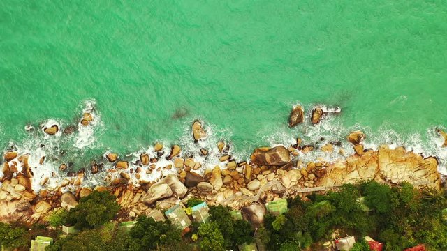 Beautiful rocky coast Koh Phangan, Thailand. Emerald wavy sea washing rocks on the island edge