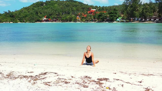 Young blonde woman enjoying facing the sun while practicing yoga. Nature connectedness, spirituality and mind relief. Thailand