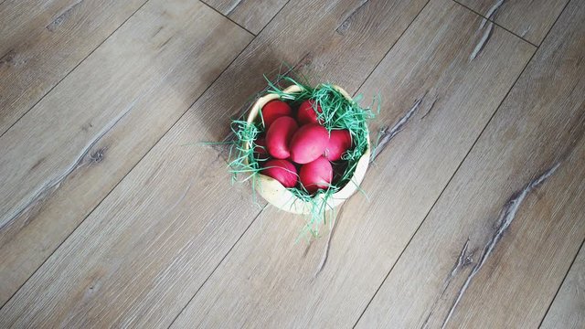 Traditional red Easter eggs in yellow nest shaped bowl with grass decoration